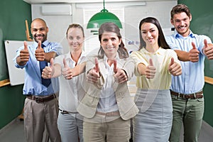 Business team looking at camera and giving thumbs up