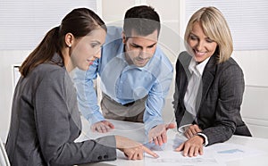 Business team of man and woman sitting around a table talking to