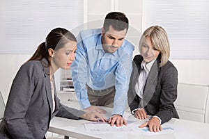 Business team of man and woman sitting around a table talking to