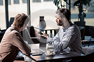 Business team on meeting discussing project with digital tablet in cafe