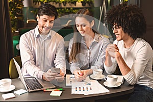 Business team on meeting discussing project with smartphone in cafe