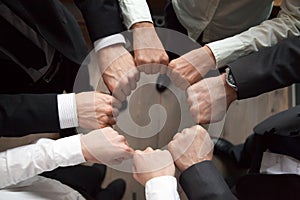 Business team put fists in circle, unity concept, top view