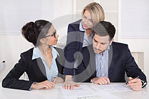 Business team sitting around a table in a meeting talking together.