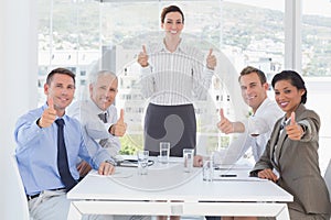 Business team smiling at camera showing thumbs up