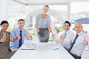 Business team smiling at camera showing thumbs up