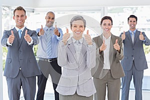 Business team smiling at camera showing thumbs up