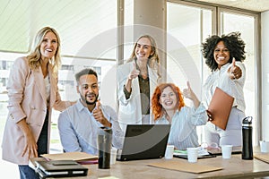 Business team smiling and showing thumb up while working in the office