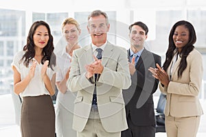 Business team standing and clapping at the camera