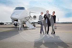 Business team standing in front of private jet