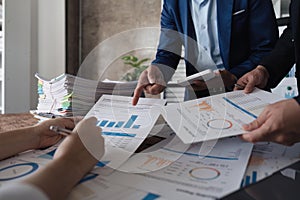 Business team using a calculator to calculate the numbers of statistic business profits growth rate on documents graph