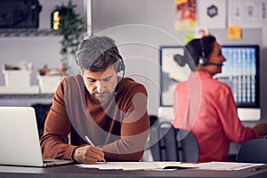 Business Team Wearing Telephone Headsets Talking To Callers In Customer Services Department