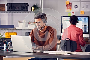 Business Team Wearing Telephone Headsets Talking To Callers In Customer Services Department