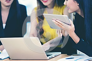 Business team work women partners discussing graph of financial in work space.   Asian women using tablet for connection technolog