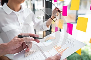 Business team working marketing growth on financial document graph report statistics, using post it notes in glass wall to writing