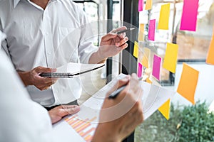 Business team working marketing growth on financial document graph report statistics, using post it notes in glass wall to writing