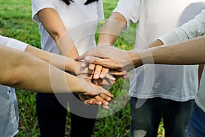 Business team working at trendy loft office. Young mixed race group of people puts palm together on the centre. Teamwork of happy