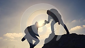 business. teamwork helps hand down business silhouette concept. a group of tourists lend a helping hand, climbing rocks