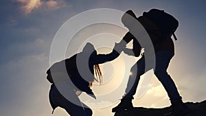 Business. teamwork helps hand down business silhouette concept. A group of tourists lend a helping hand, climbing rocks