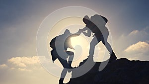 business. teamwork helps hand down business silhouette concept. a group of tourists lend a helping hand, climbing rocks