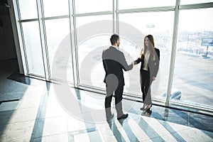 Business, teamwork, partnership, cooperation and people concept - business people shaking hands over panoramic office