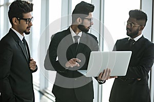 Business teamwork - three indian corporate businessmen working together on laptop