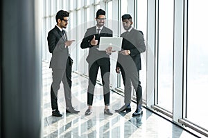 Business teamwork - three indian corporate businessmen working together on laptop