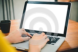 Woman hands typing laptop computer with blank screen on table in coffee shop.