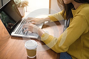 Digital lifestyle working outside office. Woman hands typing laptop computer with blank screen on table in coffee shop. photo