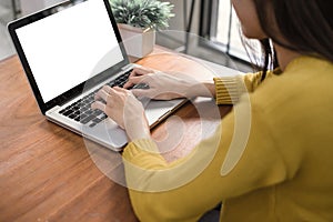 Woman hands typing laptop computer with blank screen on table in coffee shop. Blank laptop screen mock up for display of design.