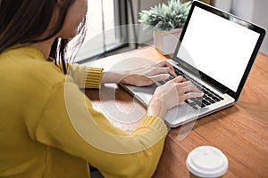 Woman hands typing laptop computer with blank screen on table in coffee shop. Blank laptop screen mock up for display of design.