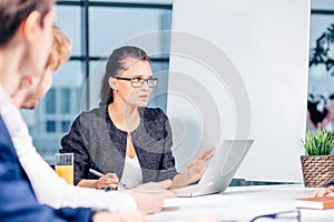 Business, technology and office concept - smiling female boss talking to team