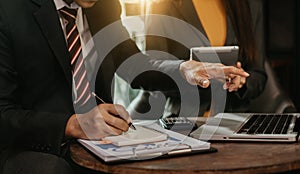 Business technology and office concept - two businessmen with take notes and laptop and papers having discussion in modern office