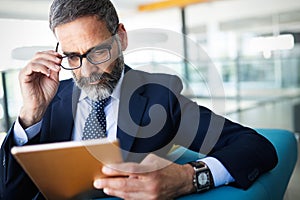 Business, technology and people concept - senior businessman with tablet pc working in office