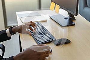 Business, Technology and Work Place Concept. Closeup of Black businessman  hand working desktop computer with keyboard, mouse and