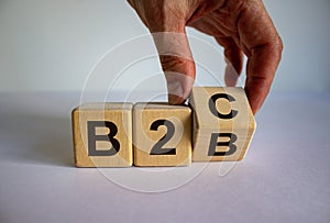 Business to Business or Busness to Consumer. Hand turns a cube and changes the expression `B2C` to `B2B` or vice versa. Busine