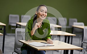 Business training. Young happy woman, female office worker sitting at desk in the office and smiling, listening to coach