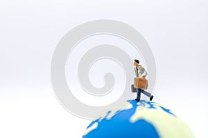 Business Travel and Global Concept. Close up of businessman traveler miniature figure with baggage running on mini world ball on