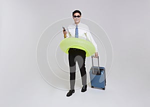 Business travel summer time. Asian businessman holding luggage and swim inflatable ring going to travel on summer holidays