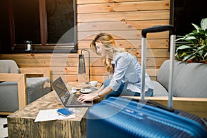 Business, travelling concept. Side view of pretty woman smiling, typing and looking on the laptop, while sitting on the