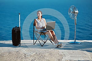 Business travelling and remote work concept. Life work balance, freelance idea. Woman working with laptop on beach.