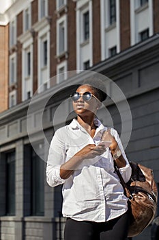 African american woman with backpack walking outdoor and talking on mobile phone