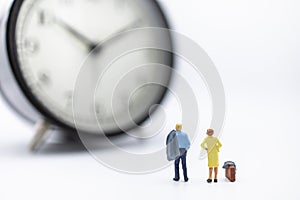 Business Trip and Time Concept. Two businessman and woman miniature figure people with suitcase standing and looking to vintage
