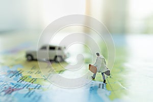 Business Trip and Travel Concept. Close up of businessman miniature figure with handbag suitcase running on colorful world map to
