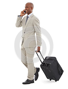 Business trip. A young AfricanAmerican businessman speaking on his phone while walking with luggage. photo