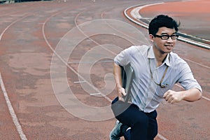 Business vision concept. Confident young Asian businessman with laptop ready run to forward on race track.