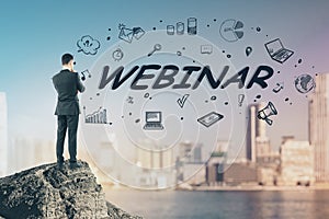 Business webinar concept with businessman on rock top and hand drawn social media icons.Double exposure