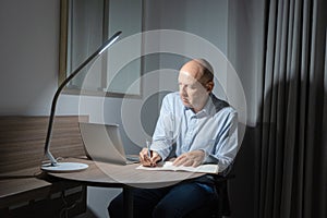 Business white senior, caucasian freelance man person working late from home at night, thinking about problem with computer