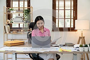 Business woman or accountant working on laptop computer with financial document, graph diagram and calculator on office