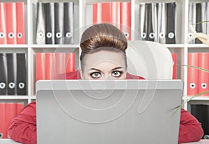 Business woman afraid and hiding behind the computer