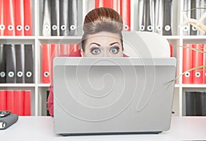 Business woman afraid and hiding behind the computer
